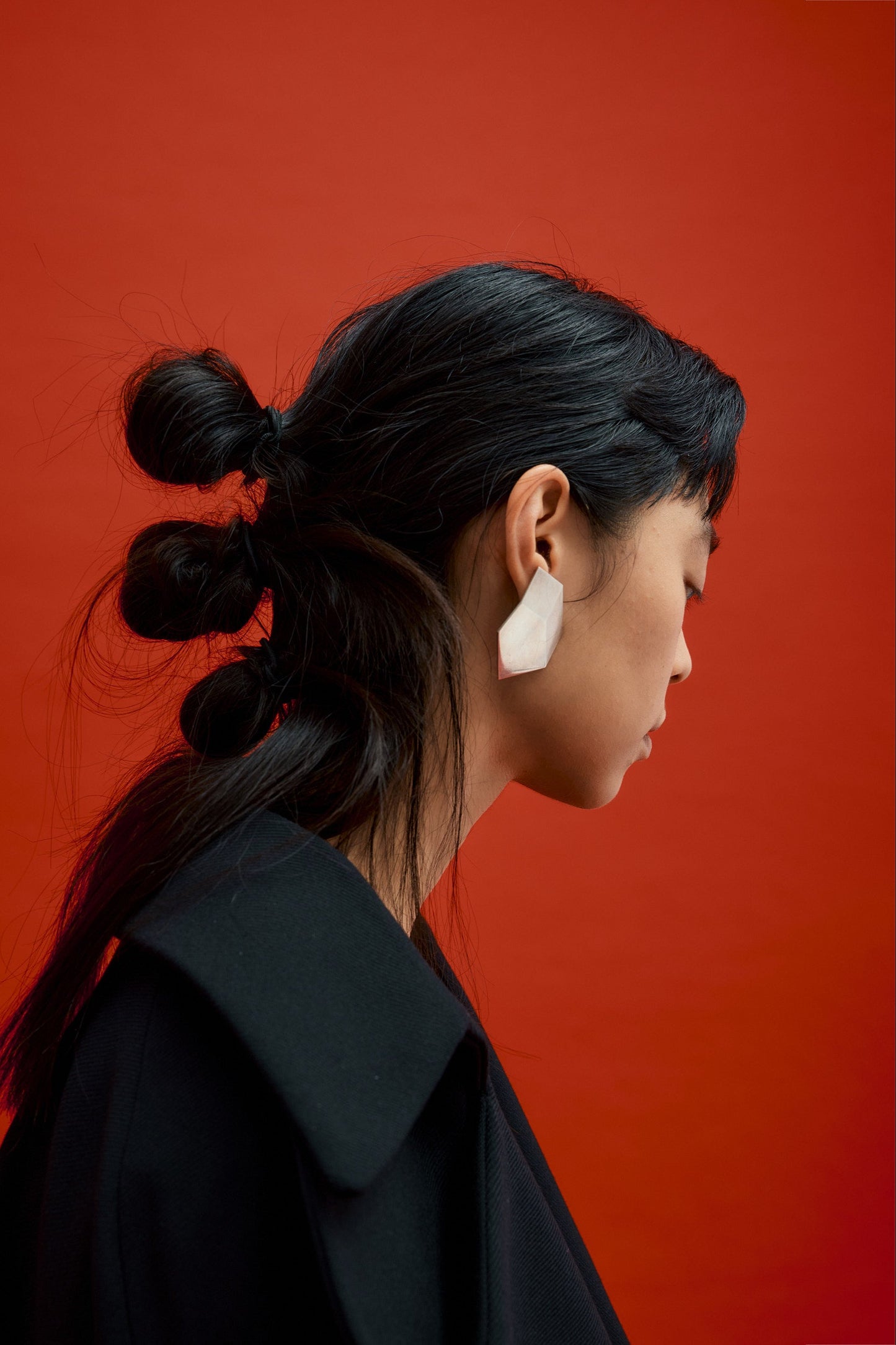 Model wearing architectural sterling silver earrings with sculptural geometric silhouette and minimalist contemporary form.