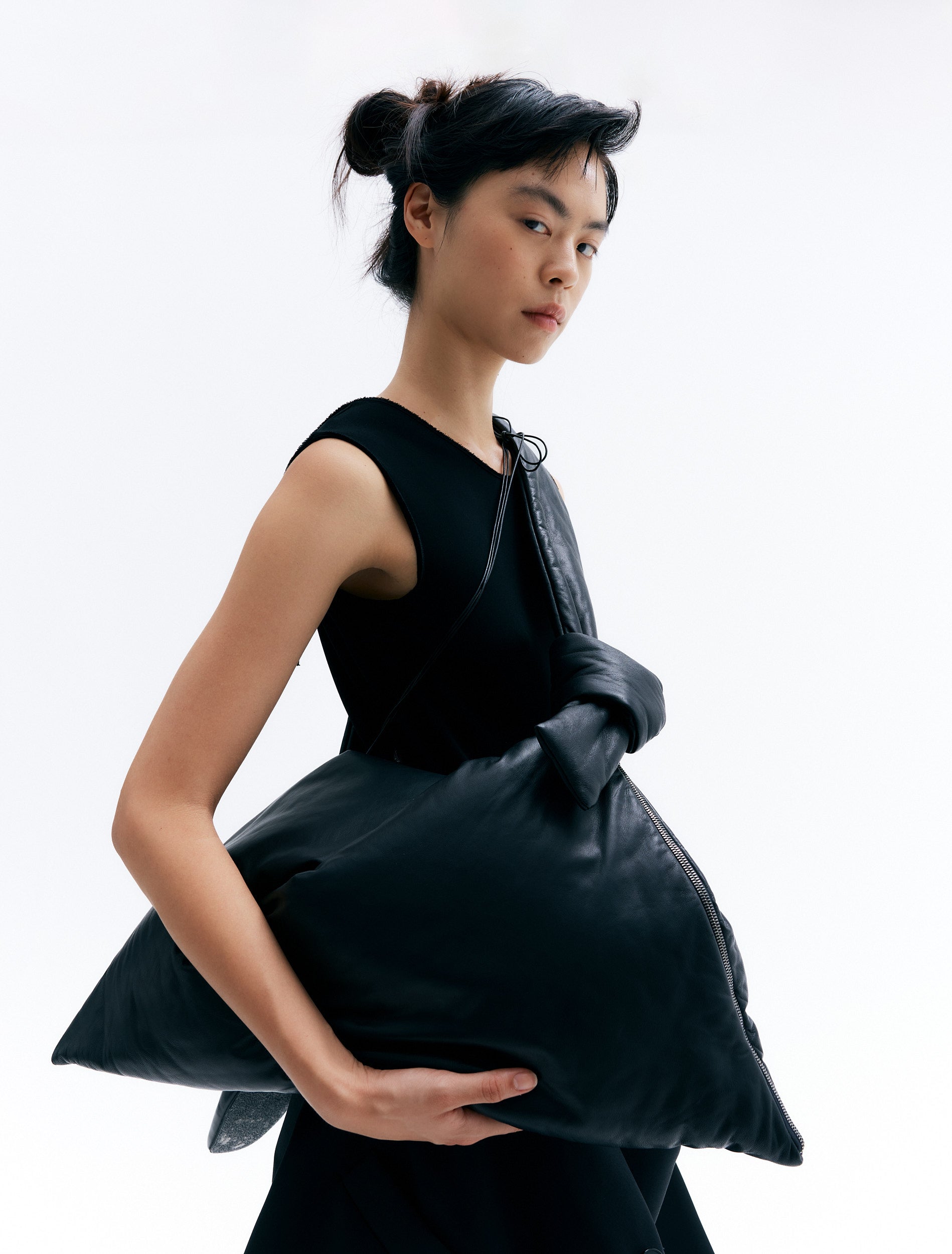 CARA carrying padded lambskin leather bag with twisted handle and zip closure in a unique triangular design.