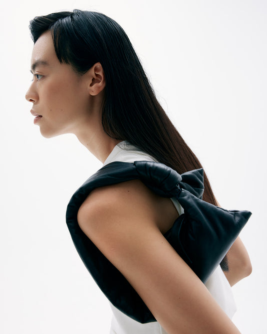 Closeup of CARA carrying padded lambskin leather Luna minibag with a knotted handle and zip closure