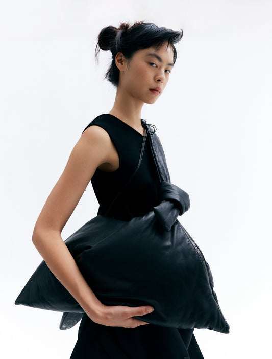 CARA carrying padded lambskin leather bag with twisted handle and zip closure in a unique triangular design.