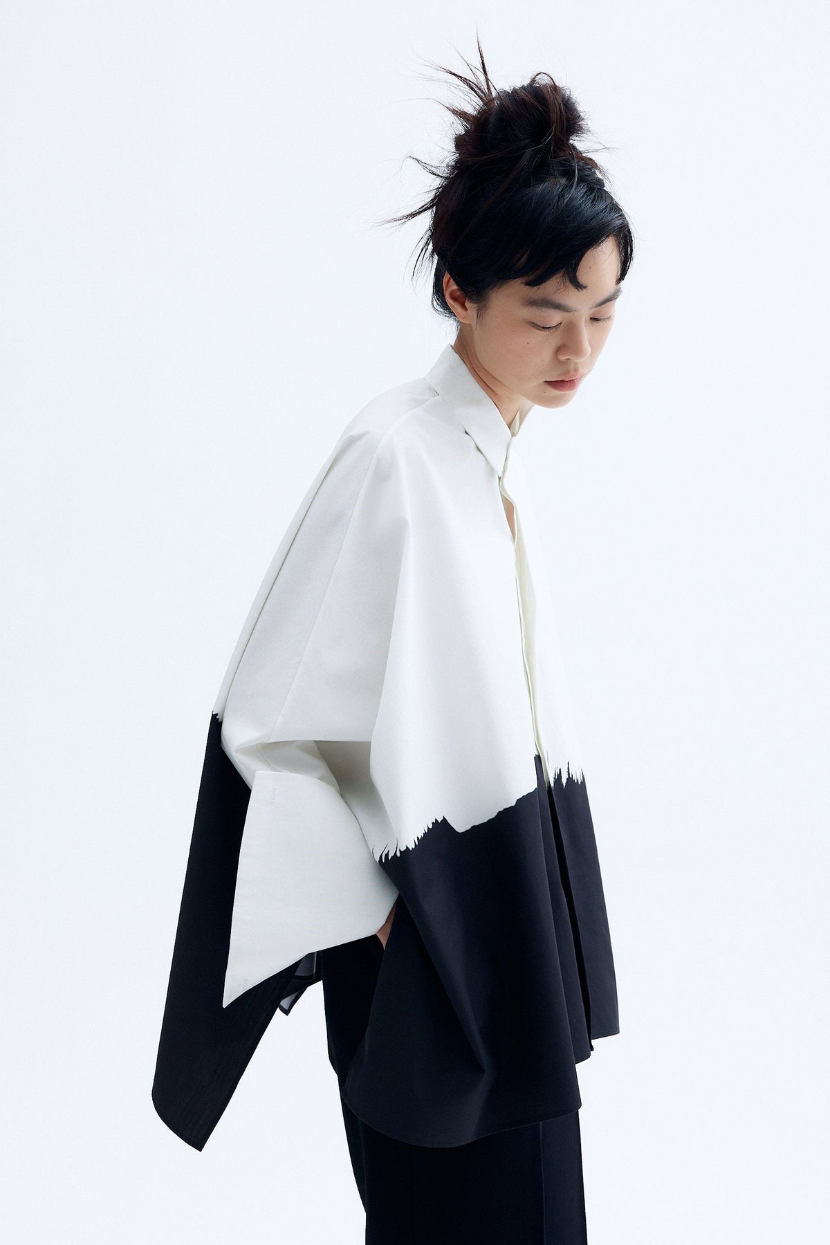 Model wearing architecture inspired cotton kimono shirt with abstract brushstroke print and sculptural wide sleeves.