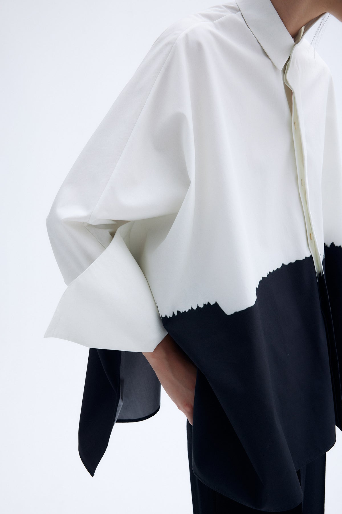 Detail of architecture inspired cotton kimono shirt with abstract brushstroke print and sculptural wide sleeves.