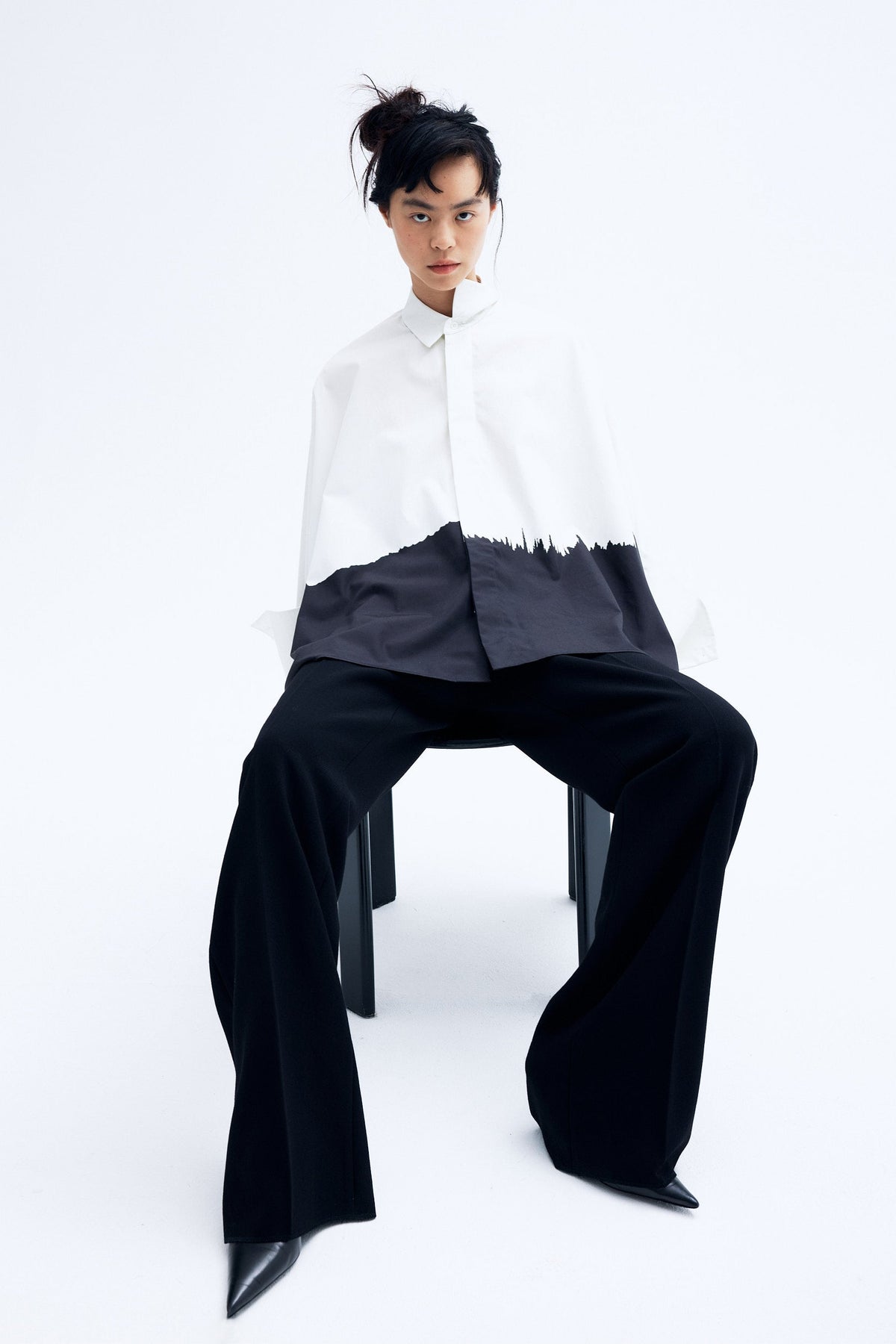 Model wearing architecture inspired cotton kimono shirt with abstract brushstroke print and sculptural wide sleeves.