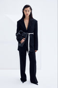 Model wearing oversized black architectural wool blazer with structured shoulders and relaxed tailoring silhouette.