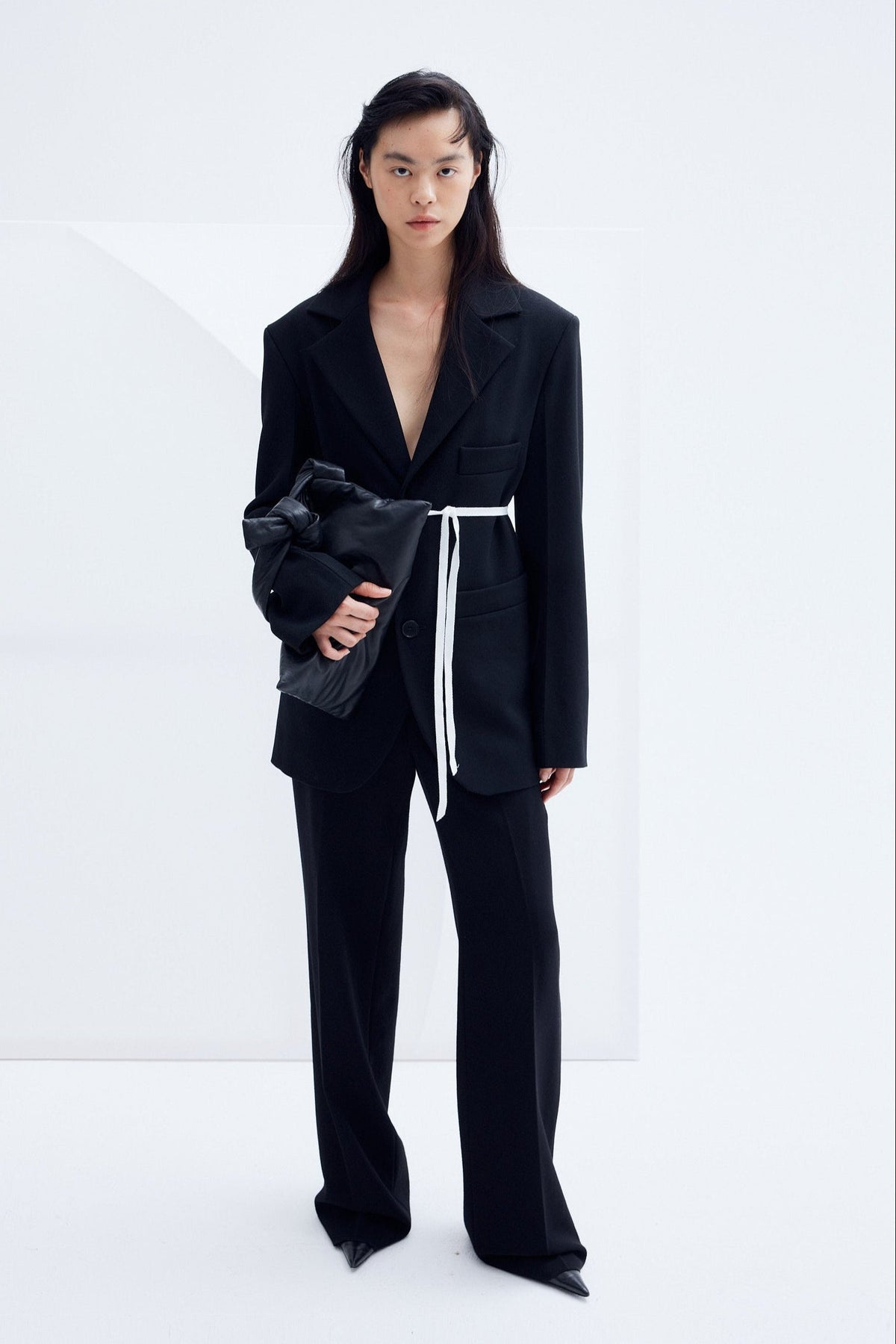 Model wearing oversized black architectural wool blazer with structured shoulders and relaxed tailoring silhouette.