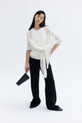 Model carrying compact padded lambskin pouch with sculptural architectural silhouette.