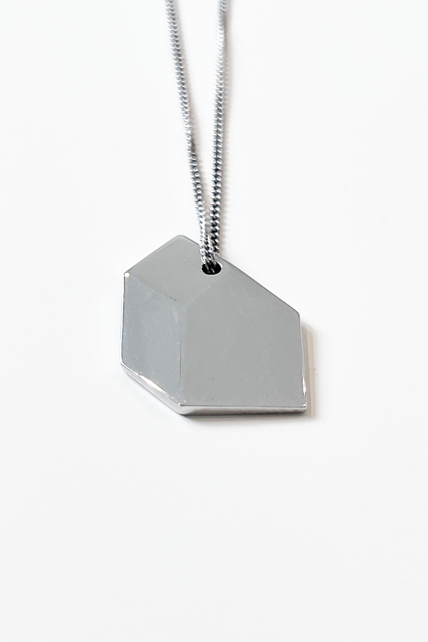 Close-up of sculptural necklace crafted from solid 925 sterling silver with geometric pendant.