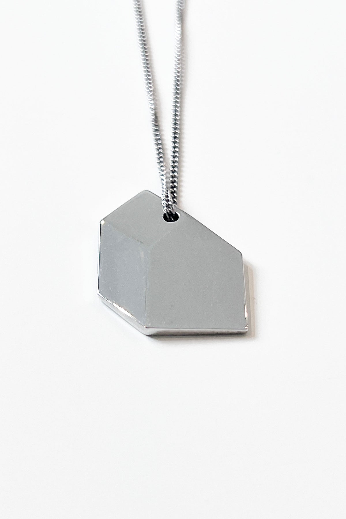 Close-up of sculptural necklace crafted from solid 925 sterling silver with geometric pendant.
