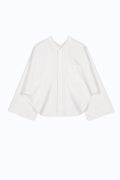 Front view of cape-inspired cotton shirt with open sleeves, patch pocket and architectural layered proportions.