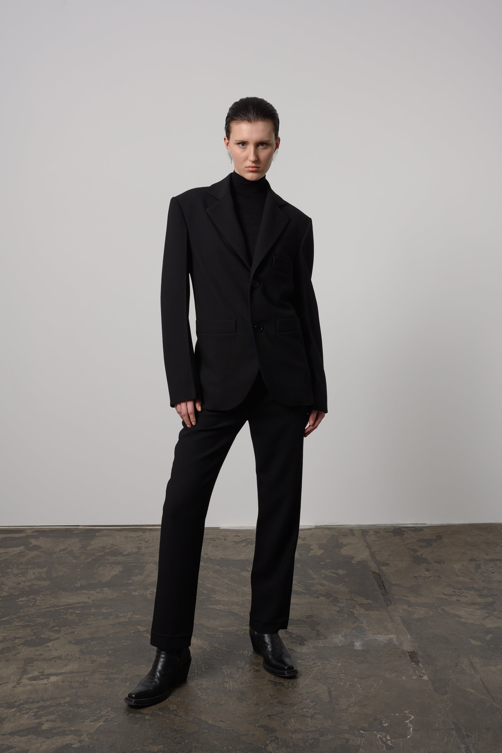 Model Zoe wearing stylish black egg-shape pants made of Italian wool gabardine, featuring a high waist and front pleats for a modern, sophisticated look