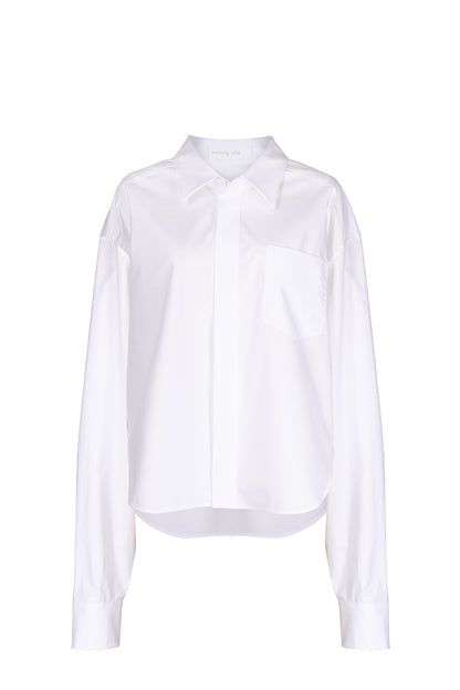 Modern white oversized shirt with a sharp collar and chest pocket, offering a sleek and versatile addition to a chic wardrobe.