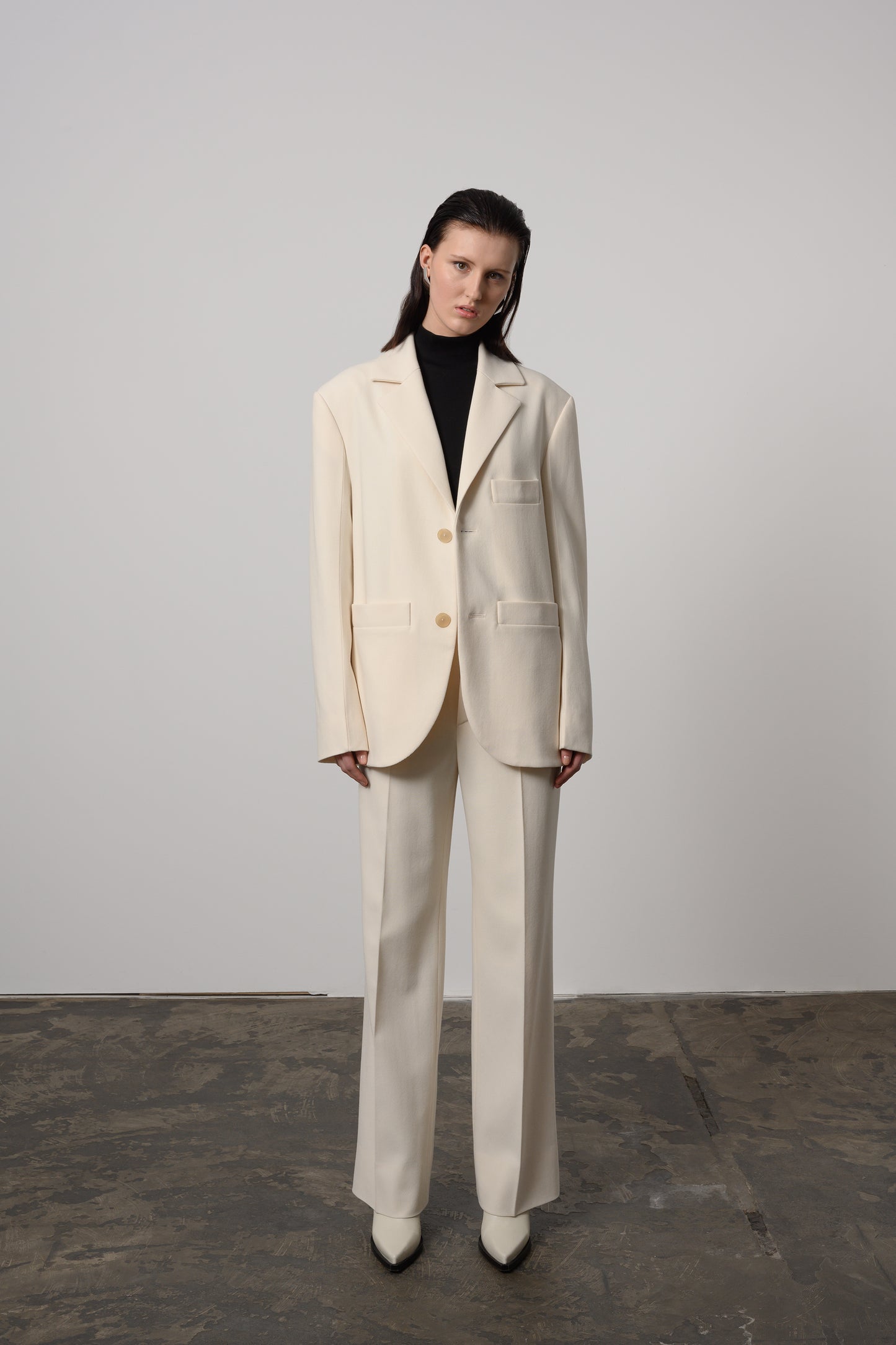 Model Zoe wearing classic off-white oversized unisex blazer made from Italian wool, featuring notched lapels and a double-button closure for a timeless and sophisticated look.