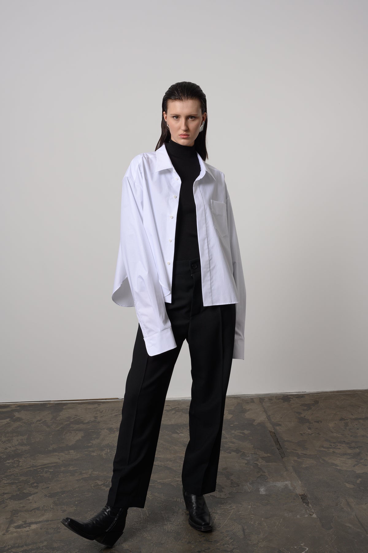 Modern white oversized shirt with a sharp collar and chest pocket, offering a sleek and versatile addition to a chic wardrobe.